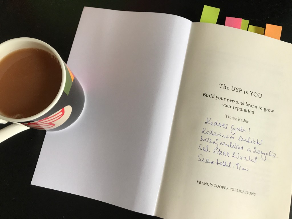 English breakfast tea with a touch of milk, The USP is You book with cover open, and Timea's kind words addressing Gabriella Ferenczi, in Hungarian
